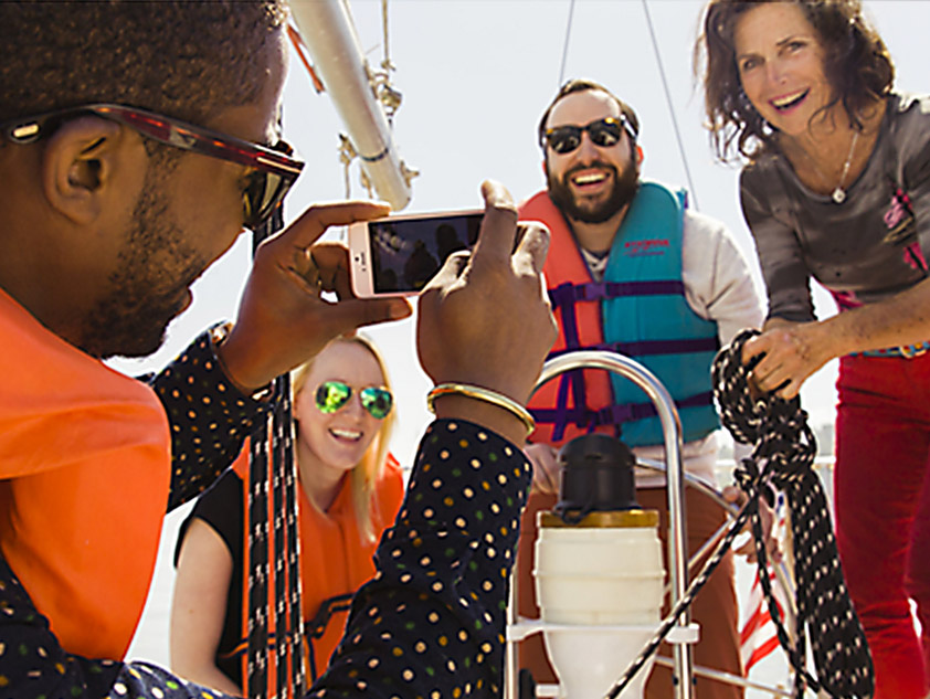 Young man taking photo of 3 other young people on a boat during an Airbnb Experience